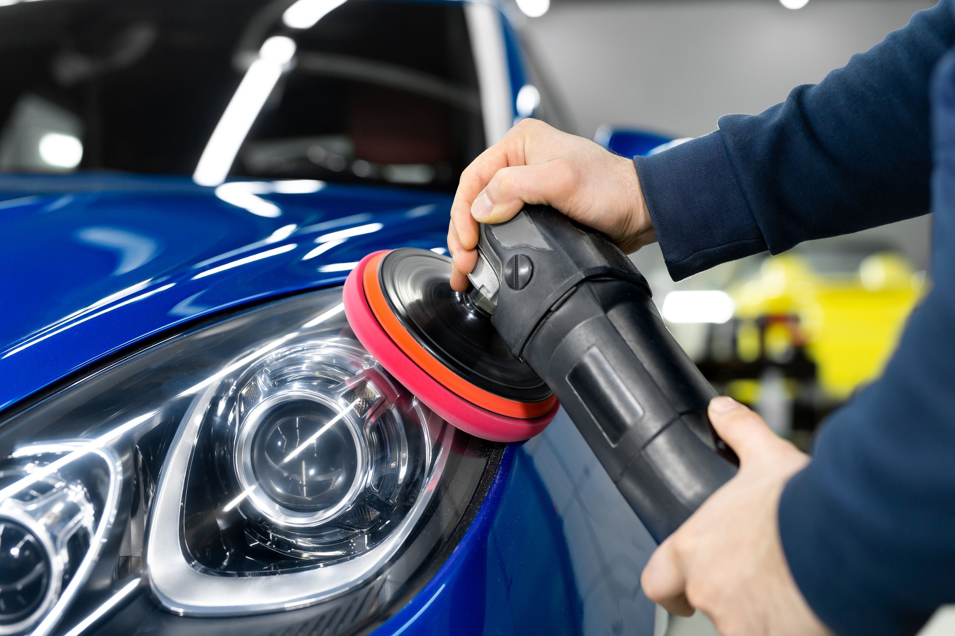 Professional detailing a car in car studio, hands with orbital polisher, scratching remover, vehicle care concept.