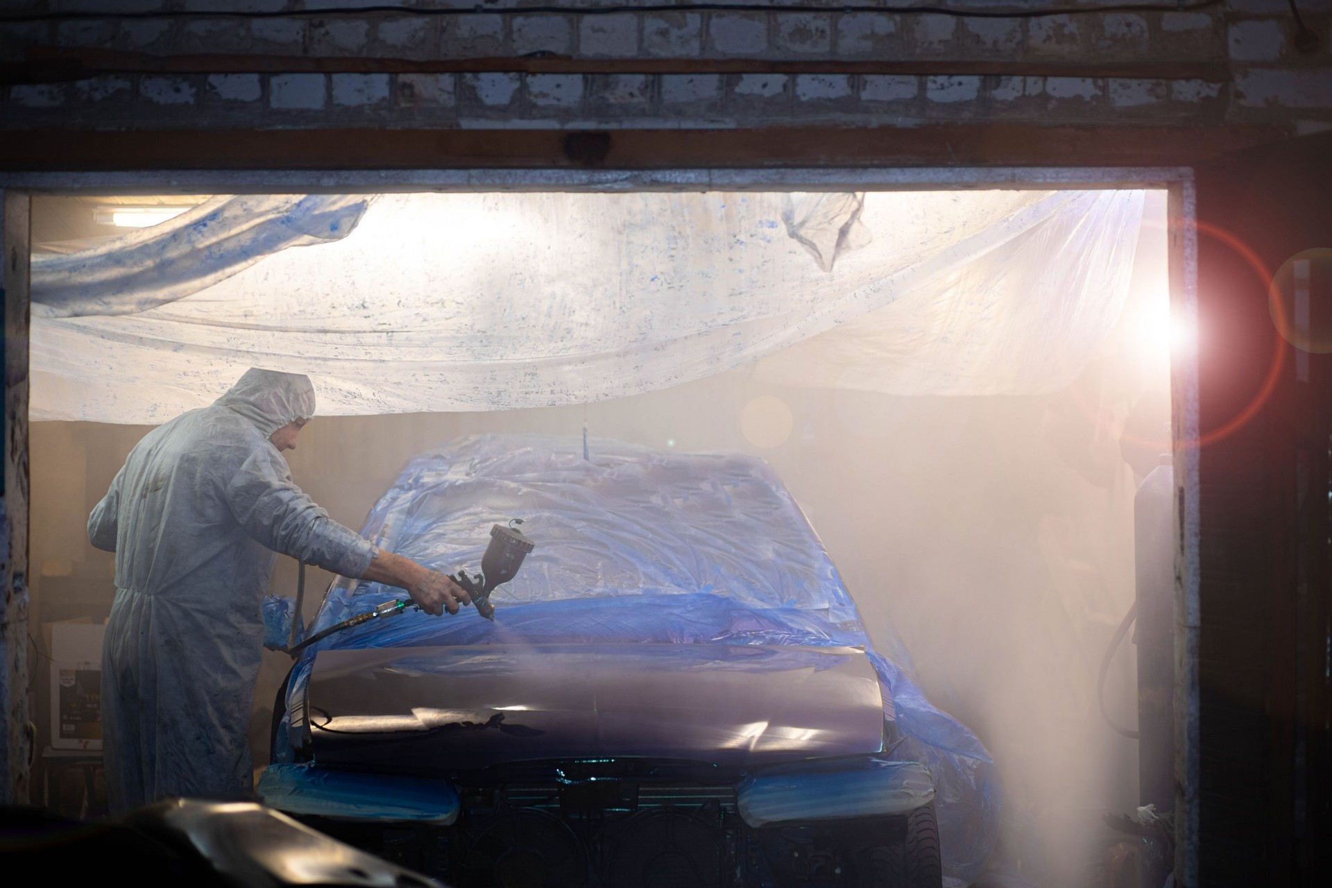 painting car body blue in car paint garage with colorful gun